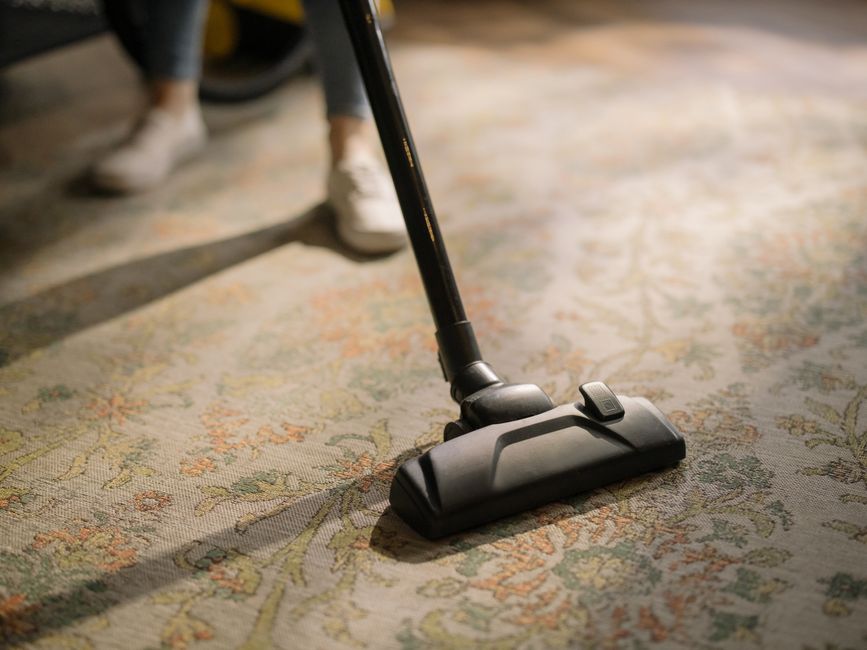 House cleaning expert vacuuming a living room carpet
